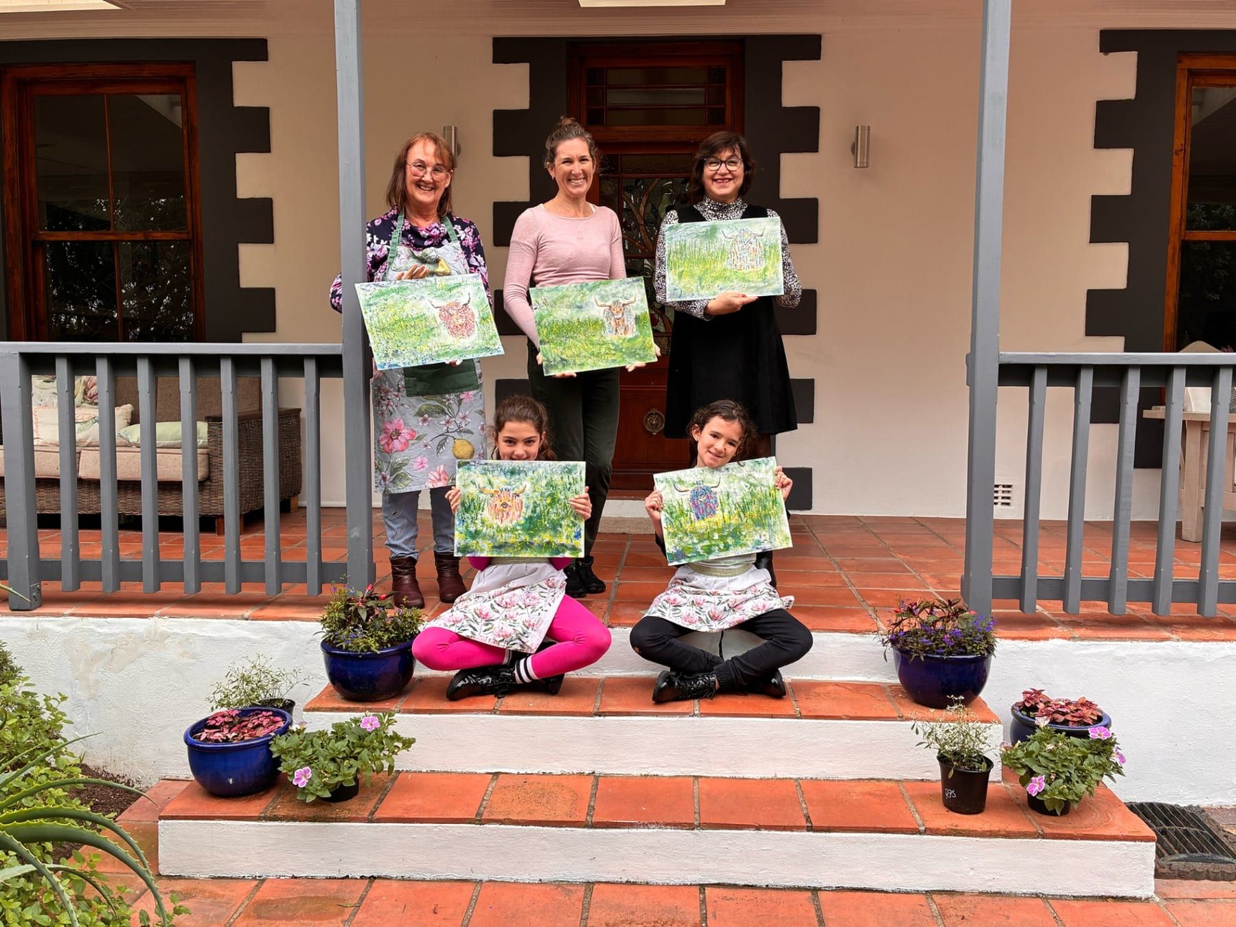 Group of students on the stoep with finished paintings
